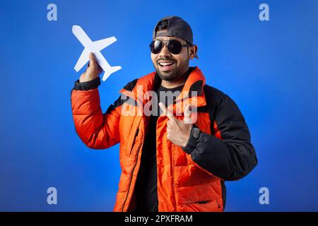Travel destination, passenger, vacation. Man with toothy clutching paper cut airplane and pointing with fingers. Stock Photo