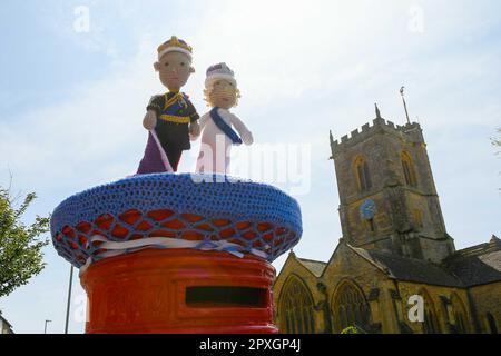 Bridport, Dorset, UK.  2nd May 2023.  A King Charles III and Queen Camilla crochet post box topper decorates a pillar box on South Street at Bridport in Dorset ahead of  the King’s coronation on Saturday.  Picture Credit: Graham Hunt/Alamy Live News Stock Photo