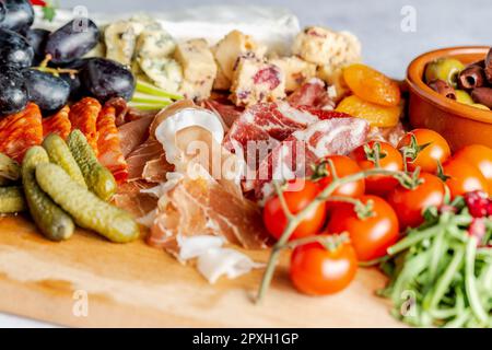 A mix of different snacks and appetizers on a wooden board Stock Photo