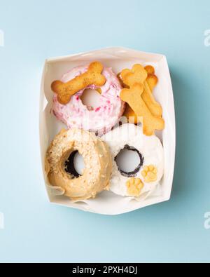 A selection of freshly-baked donuts and cookies arranged in a white box resting on a blue surface Stock Photo