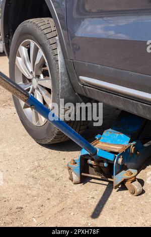 The car is raised on a pneumatic jack to change winter tires to summer tires. Tire service. Seasonal change or repair of wheels. A car lifted on a jac Stock Photo