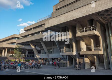 People at cafe, bar, restaurant outside National theatre brutalist style building by Denys Lasdun in the South Bank Complex opened in 1976. London. Stock Photo
