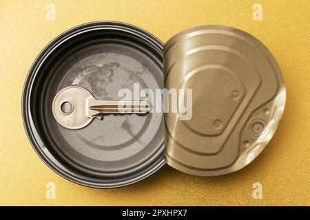 Opened tin can with a door key inside. Conceptual image. Stock Photo