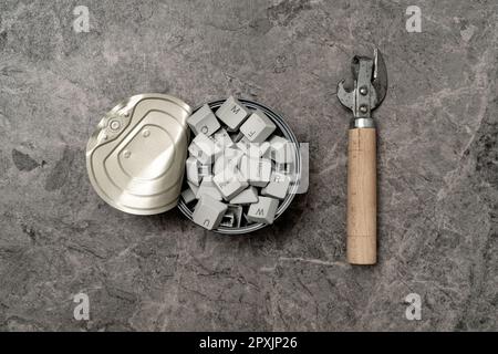 Knowledge seeking concept: can opener and tin can full of computer keyboard keys on the stone background Stock Photo