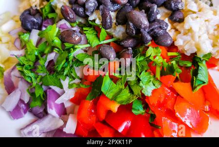Vegetable dish soup with beans greens rice noodles onions tomato and garlic on a white plate bowl with fork or spoon in Mexico. Stock Photo