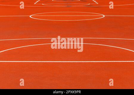 Minimalist abstract background of an orange tartan outdoor basketball court with white lines. Selective focus. Stock Photo