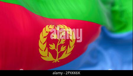 Close-up view of the Eritrea national flag waving. Eritrea flag is red triangle on hoist, green & blue triangles, gold emblem of olive branch & wreath Stock Photo