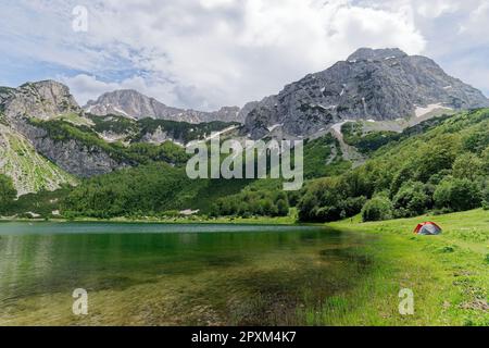Camping next to a lake surrounded by mountains. Scenic and beautiful view. Hiking life. Travel and adventurous. Nature concept. Holidays and vacation. Stock Photo