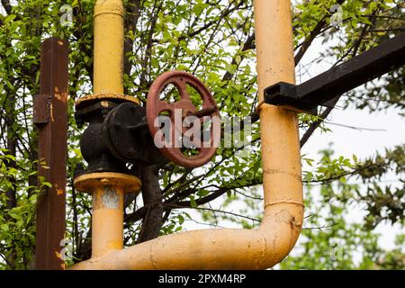 a yellow gas pipe with an old rusty valve. Gasification of housing Stock Photo