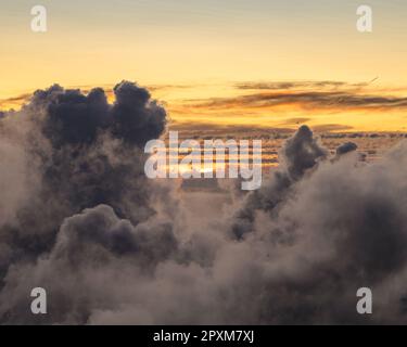 A magnificent view of a picturesque sunset, with majestic clouds and warm sunlight beaming in Stock Photo