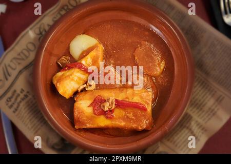 Clay casserole with a tasty Biscayne-style cod, accompanied with potatoes, red peppers and fried garlic. Stock Photo