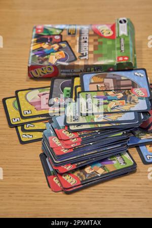 A vertical shot of a colorful uno card with a Minecraft theme on a wooden table in the foreground Stock Photo