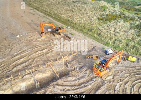 Two Hitachi Excavators on West Beach Littlehampton for major repair work to the damaged sea wall at the entrance to the River Arun. Aerial view. Stock Photo