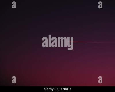 the plane and the trail in the crimson-burgundy sky. Abstract background on space or aero theme. Stock Photo