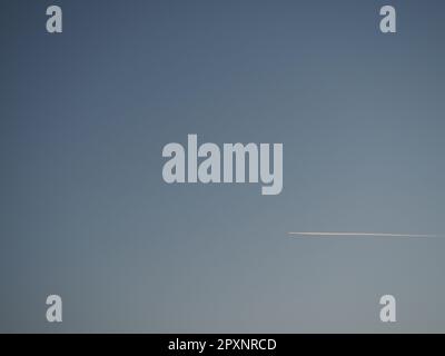 plane and trail in the evening sky blue. Abstract background on a space or aero theme. Color gradient. Stock Photo