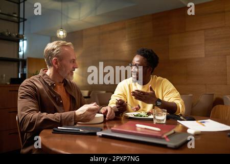 Two colleagues discussing plans while having meeting during business lunch in restaurant Stock Photo