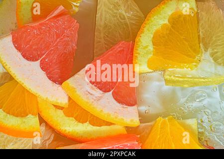 Slices of grapefruit, orange and pomelo in water on white background. Pieces of grapefruit, orange fruit and honey pomelo in liquid with bubbles. Slic Stock Photo