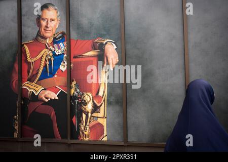 With five days to go before the coronation of King Charles III, following the death of Queen Elizabeth last year, a Muslim woman walks past a portrait of the new king on Park Lane, on 2nd May 2023, in London, England. Stock Photo