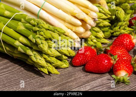 Green asparagus, white asparagus and fresh strawberries decorated on a rustic wooden table Stock Photo