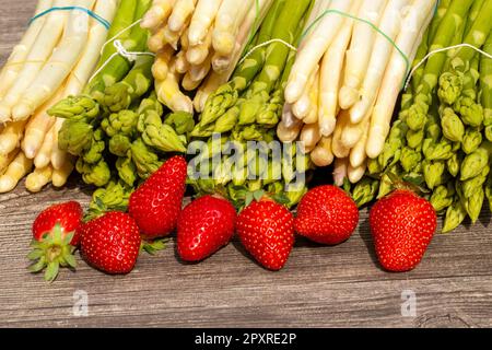 Green asparagus, white asparagus and fresh strawberries decorated on a rustic wooden table Stock Photo