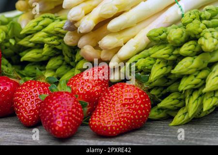 Green asparagus, white asparagus and fresh strawberries decorated on a rustic wooden table Stock Photo