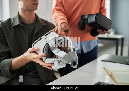Close-up of young developers testing VR glasses and discussing computer program during teamwork in office Stock Photo