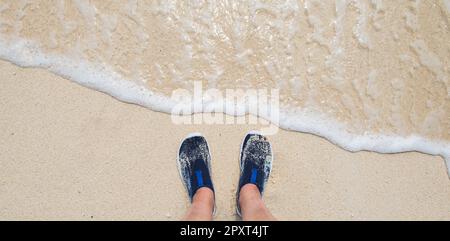 Female feet wearing water shoes or swimming shoes on the beach. Stock Photo