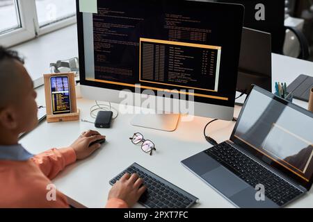 Rear view of young developer writing security codes on computer while working at his workplace in IT office Stock Photo
