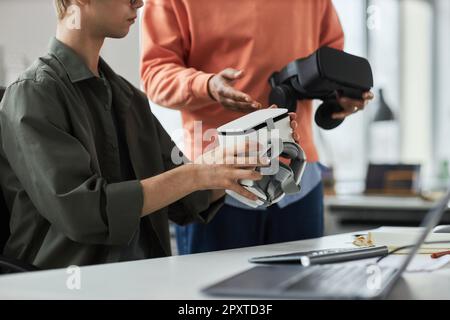 Close-up of two programmers testing new computer program in VR glasses during teamwork in office Stock Photo