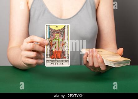 Lodz Poland April 15 2023 Justice arcana, hand holding showing tarot card during divination. Stock Photo