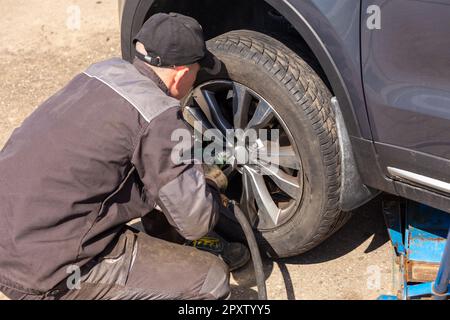 Mechanician changing car wheel in auto repair shop Stock Photo - Alamy
