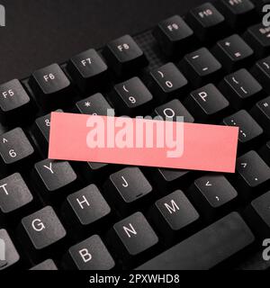 Sticker lying on black keyboard. Important message written over paper. Stock Photo