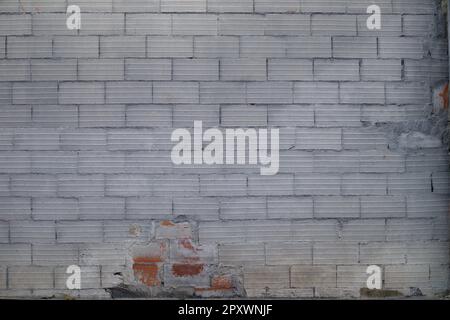 Brick wall painted in gray degraded by time and neglect in the center of a city Stock Photo