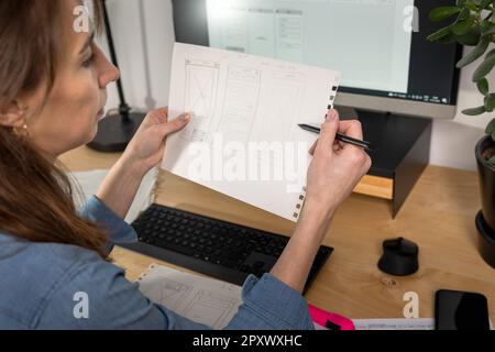 Sketch of wireframe for website. Women designer working on a mobile application, drawing on paper. Stock Photo