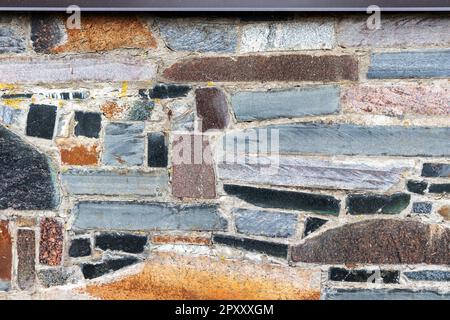 Close-up of a colorful stone wall with a large stone in the middle. Stock Photo