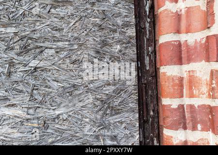 Textured straw and red brick wall. Stock Photo