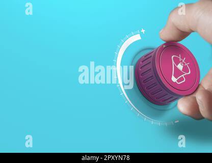 Man turning a pink knob with a megaphon icon. Brand communication strategy and advertising concept over blue background with copy space. Stock Photo