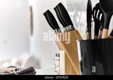 Plastic kitchen utensils in stand with clean dishes on tablecloth