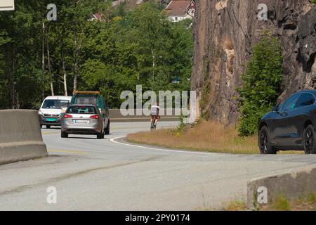 Kristiansand, Norway - August 01 2021: Cyclist in heavy traffic on narrow roads. Stock Photo