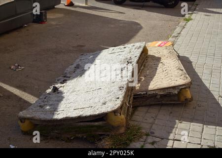 Image of some old mattresses, discarded between some garbage containers and the sidewalk in a big city Stock Photo