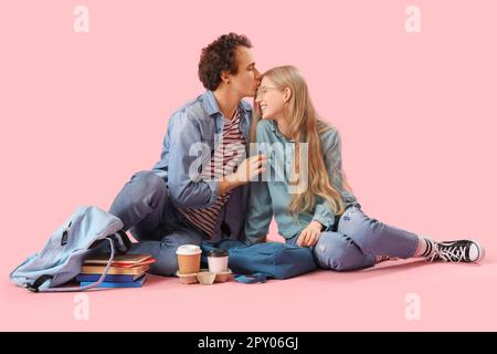 Teenage couple sitting on pink background Stock Photo