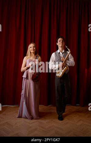 Sax man and woman fiddler duet. Musical duo jazz band on the stage Stock Photo