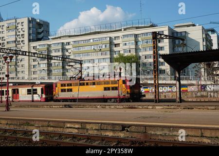 Dated train owned by small passenger transport company coming to North railway station in Bucharest on sunny day Stock Photo