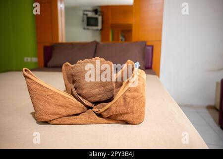 Yellow towel on bed decoration in bedroom interior, Freshly laundered fluffy towels, Towel in hotel room, Beautifully folded toiletries Stock Photo