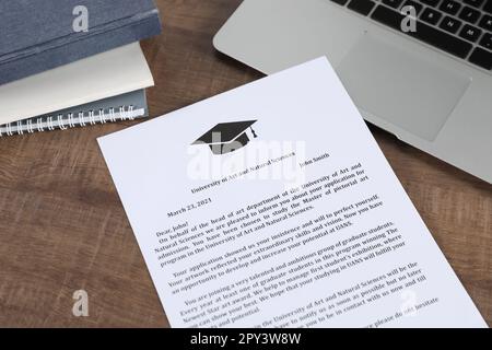 Acceptance letter from university, books and laptop on wooden table, above view Stock Photo