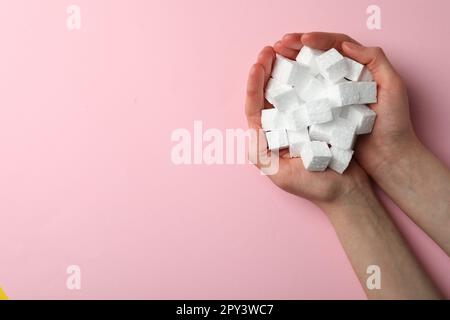 Woman with handful of styrofoam cubes on pink background, top view. Space for text Stock Photo