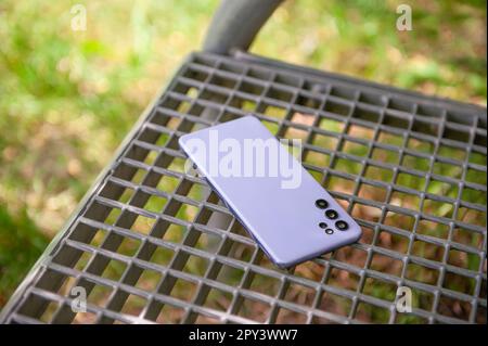 Smartphone forgotten on metal bench outdoors. Lost and found Stock Photo