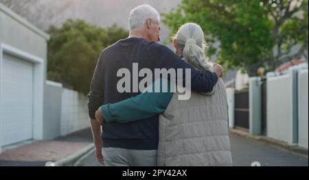A walk outside is all we needed. a senior couple walking down the street outside with their arms around each other. Stock Photo