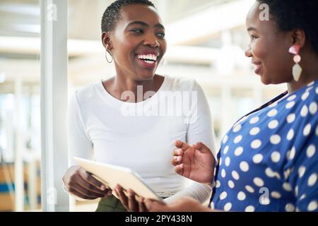 The more freely the information flows the better the collaboration. two young businesswomen using a digital tablet in a modern office. Stock Photo