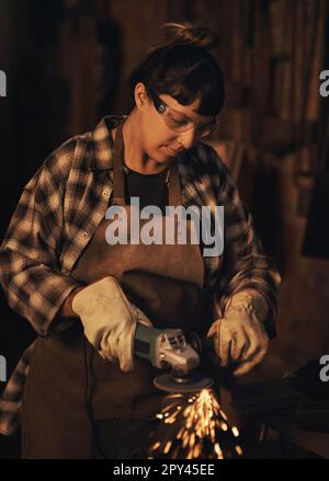 Pouring passion into every project. a young woman using an angle grinder while working at a foundry. Stock Photo